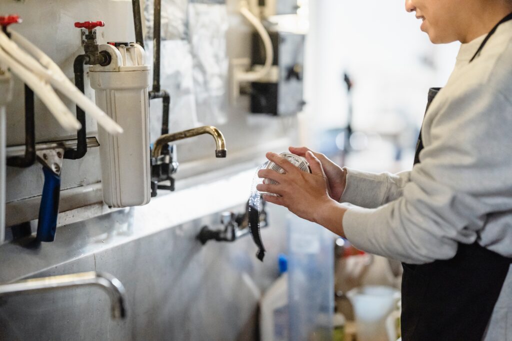 Person washing hands in commercial kitchen sink.