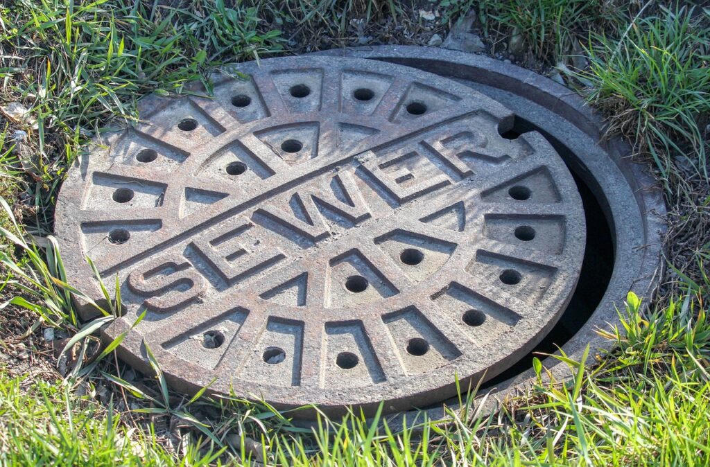 Sewer manhole cover surrounded by grass, representing plumbing infrastructure relevant to Frost & Kretsch Plumbing services in Washington.