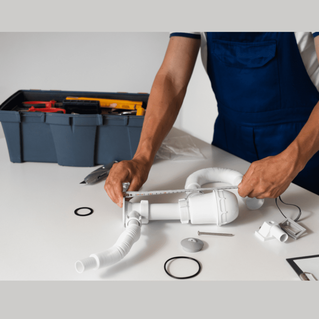 Plumber measuring plumbing parts with tools on a workbench, showcasing professional plumbing services by Frost & Kretsch Plumbing Inc in Sterling Heights.