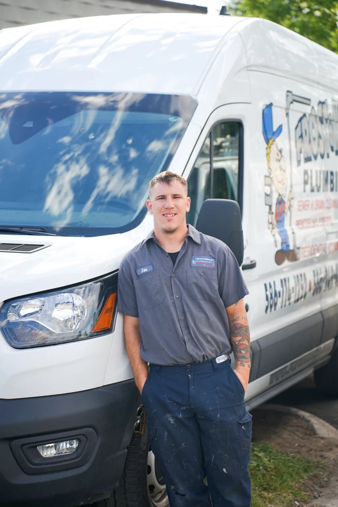 Plumber standing by service van smiling.