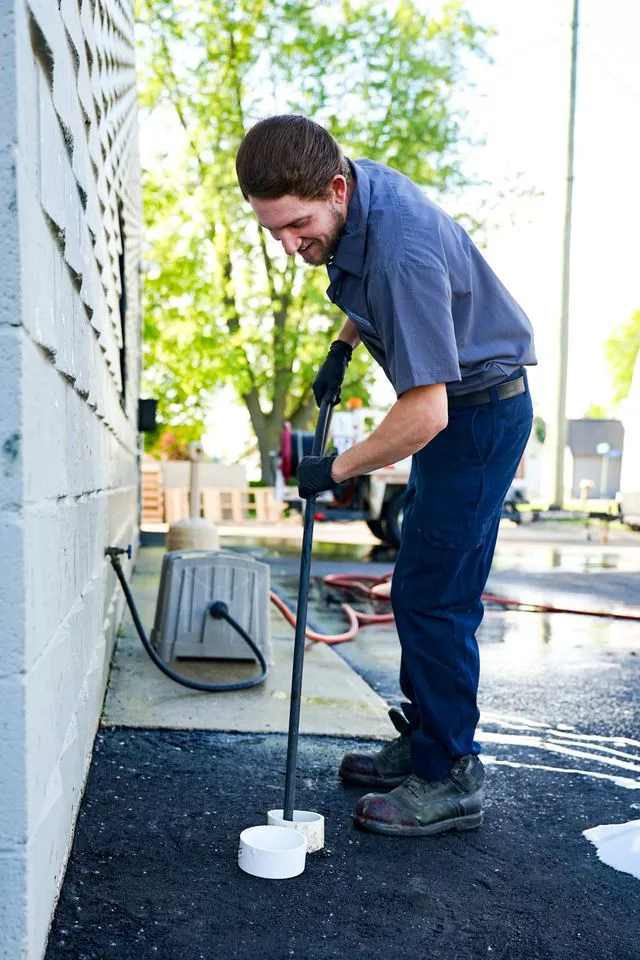 Man sealing asphalt with tool outdoors.